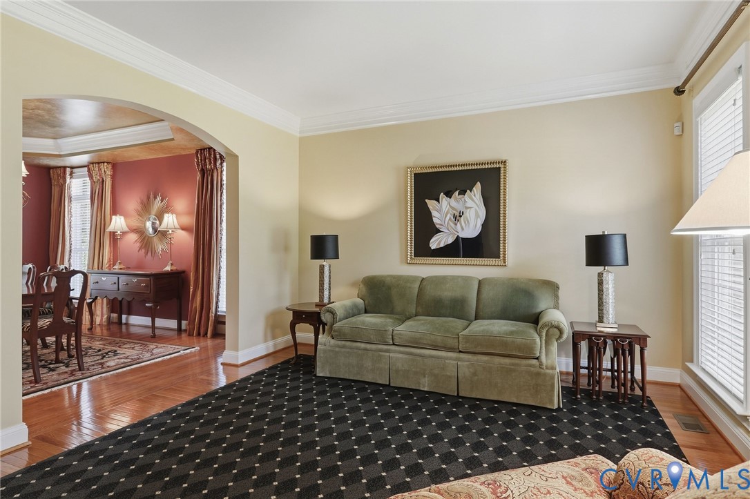 Crown molding details, arched entry, hardwood flooring, and neutral wall tones