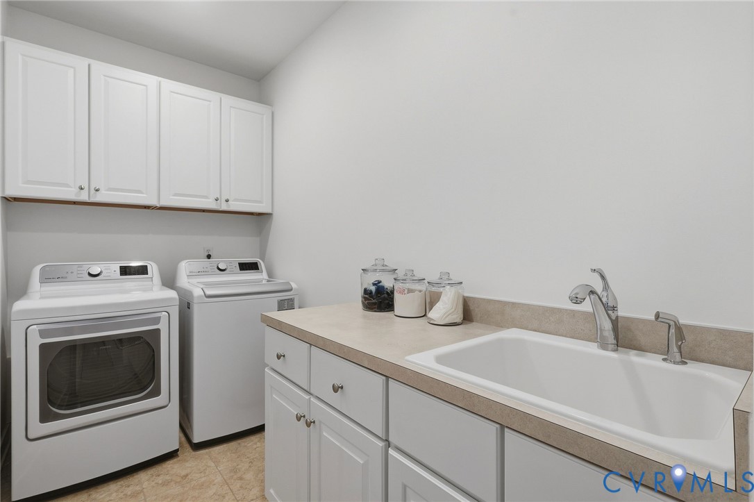 White shaker-style cabinetry, a built-in utility sink, a chrome faucet, and neutral-toned countertops