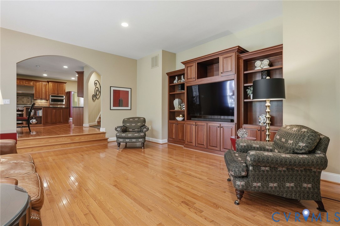Hardwood flooring throughout, built-in entertainment center, recessed lighting, and arched doorway