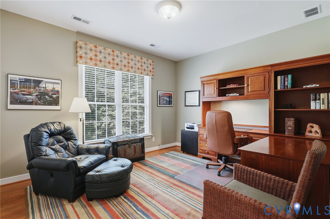 Built-in wood cabinetry and shelving, wood-finish flooring, and a multi-pane window with blinds