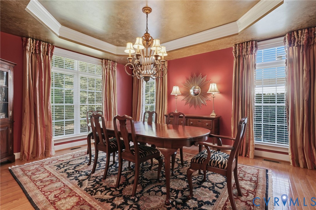 Dining area featuring wood-finish flooring, a tray ceiling, and a chandelier