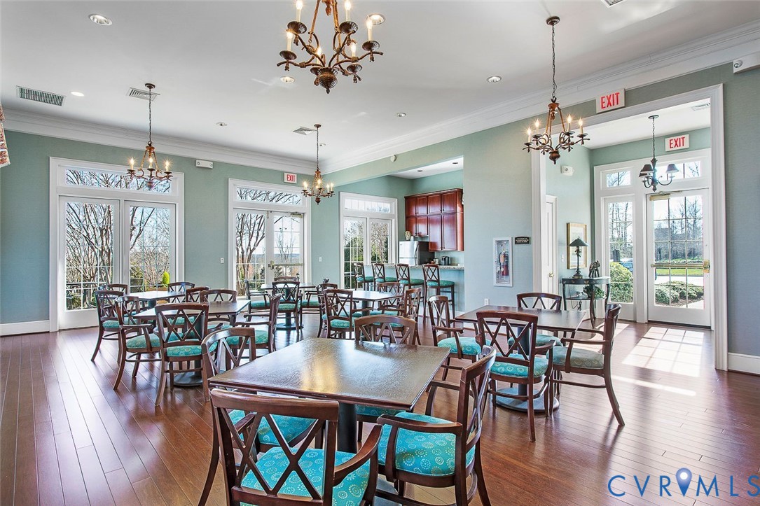 Hardwood flooring, chandelier lighting, multiple French doors, and a built-in wet bar with cabinetry
