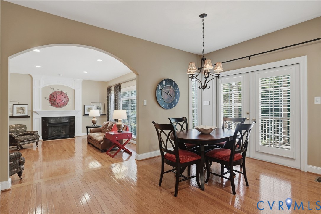 Hardwood flooring throughout, arched doorway, fireplace with mantel, recessed lighting, and French doors