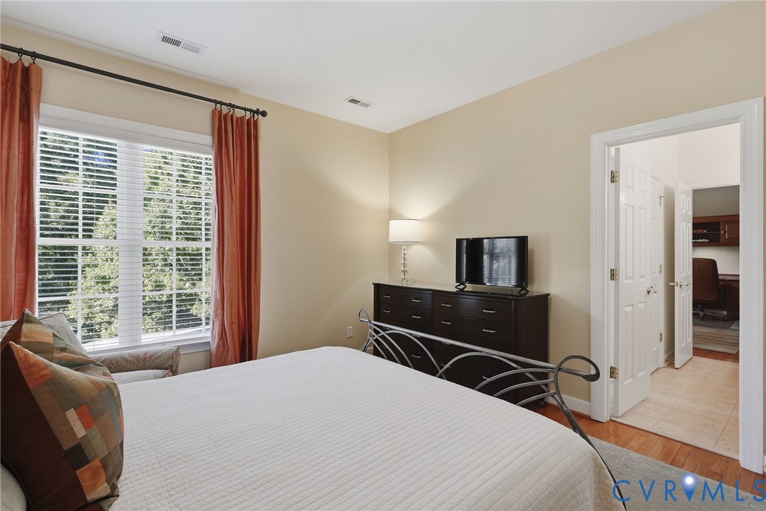 Recessed window with blinds, wood-finish flooring, and built-in closet doors