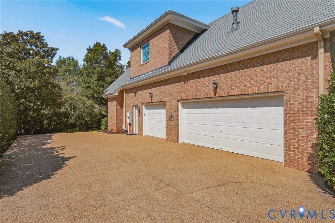 Brick exterior with a multi-car garage and a pitched shingle roof