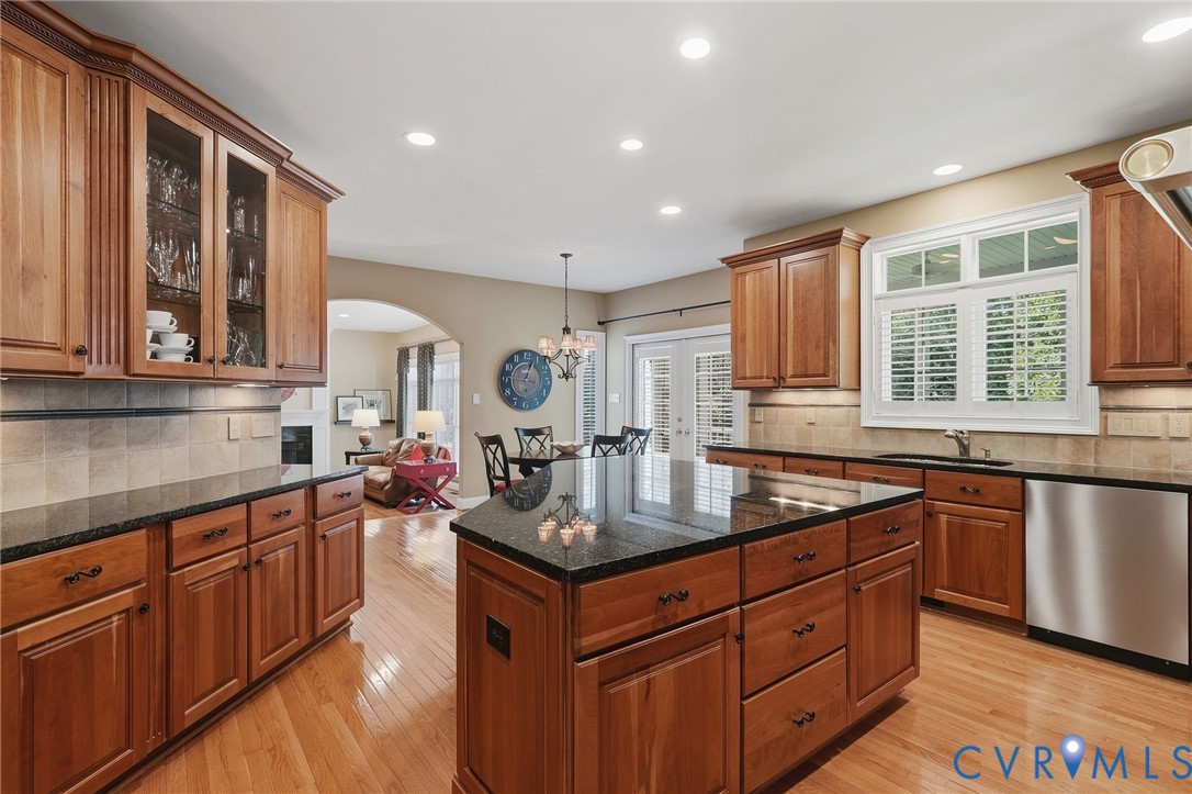 Kitchen featuring wood-finish cabinetry, dark countertops, hardwood flooring, and recessed lighting