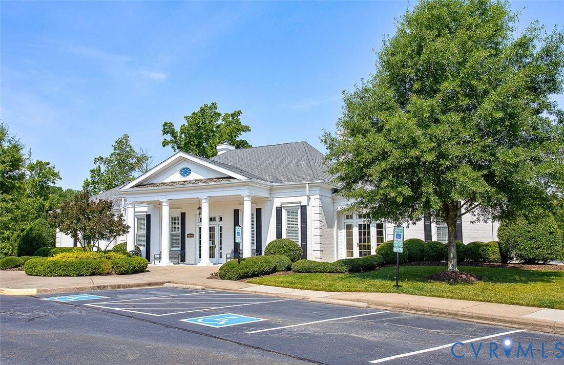 Colonial-style facade with white columns, symmetrical black shutters, a gabled roof, and extensive perimeter landscaping