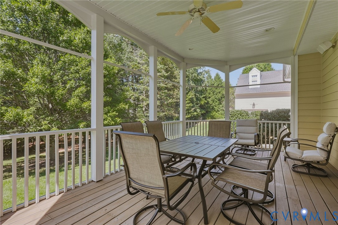 Screened porch featuring wood-finish flooring, white railing, ceiling fan, and exterior siding