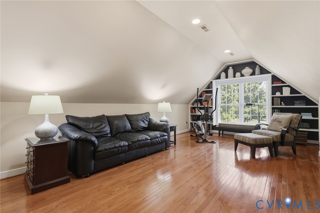 Sloped ceilings, recessed lighting, polished wood-finish flooring, built-in shelving, and a prominent window
