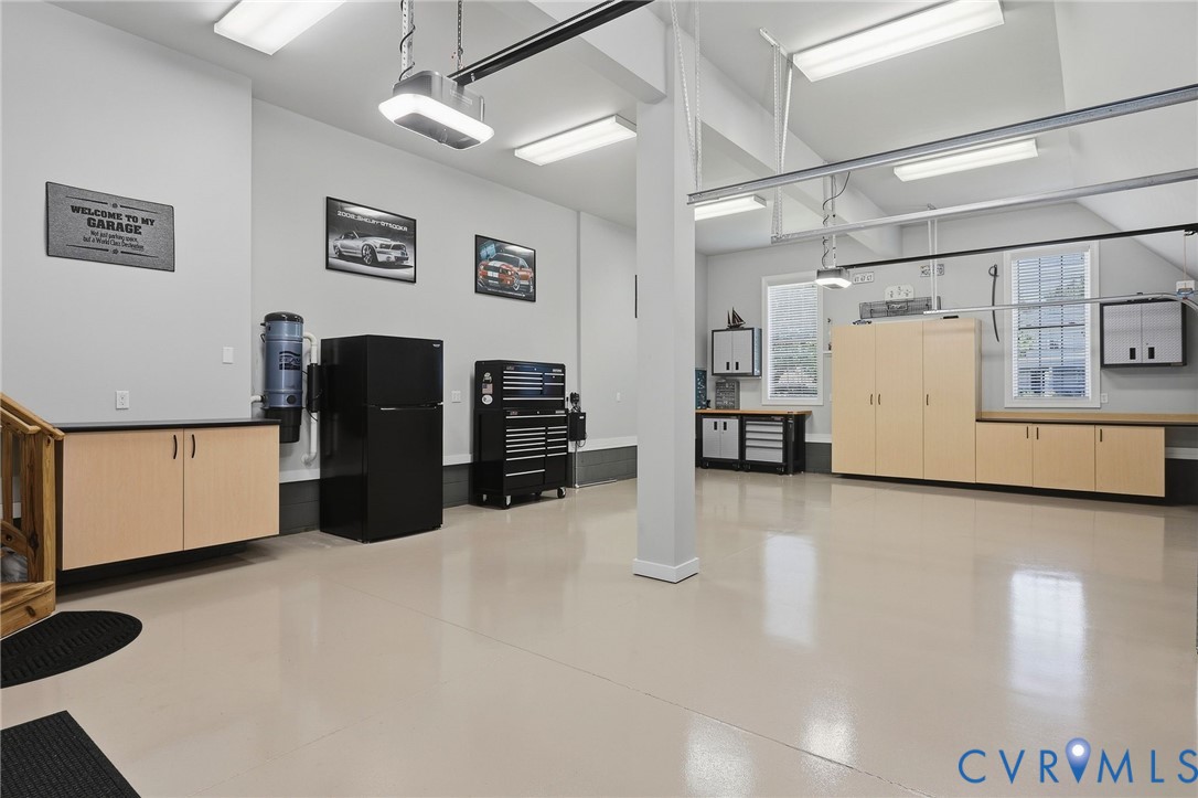 Spacious garage featuring light-toned flooring, built-in cabinetry with counter space, and wall-mounted storage units