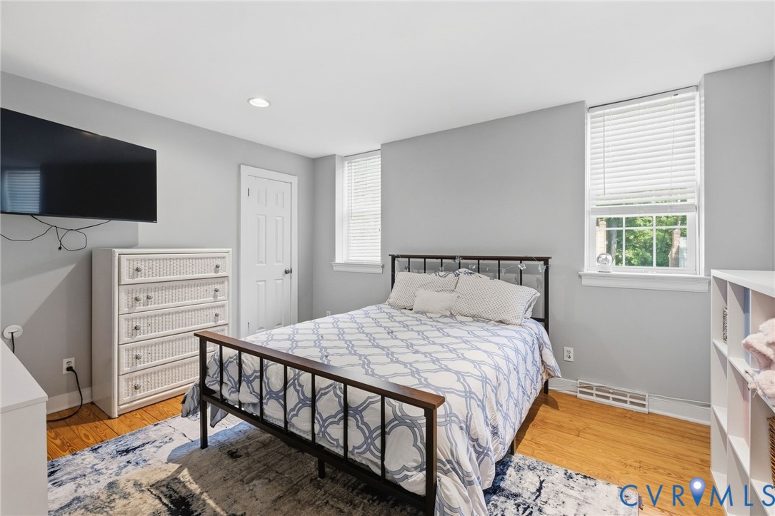 Recessed lighting, wood-finish flooring, two windows with blinds, and built-in shelving