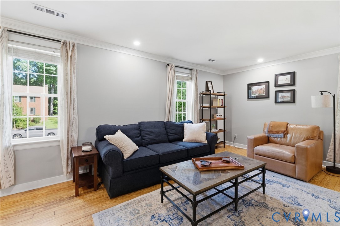 Hardwood flooring, recessed lighting, crown molding, white trim, and a window with divided lites