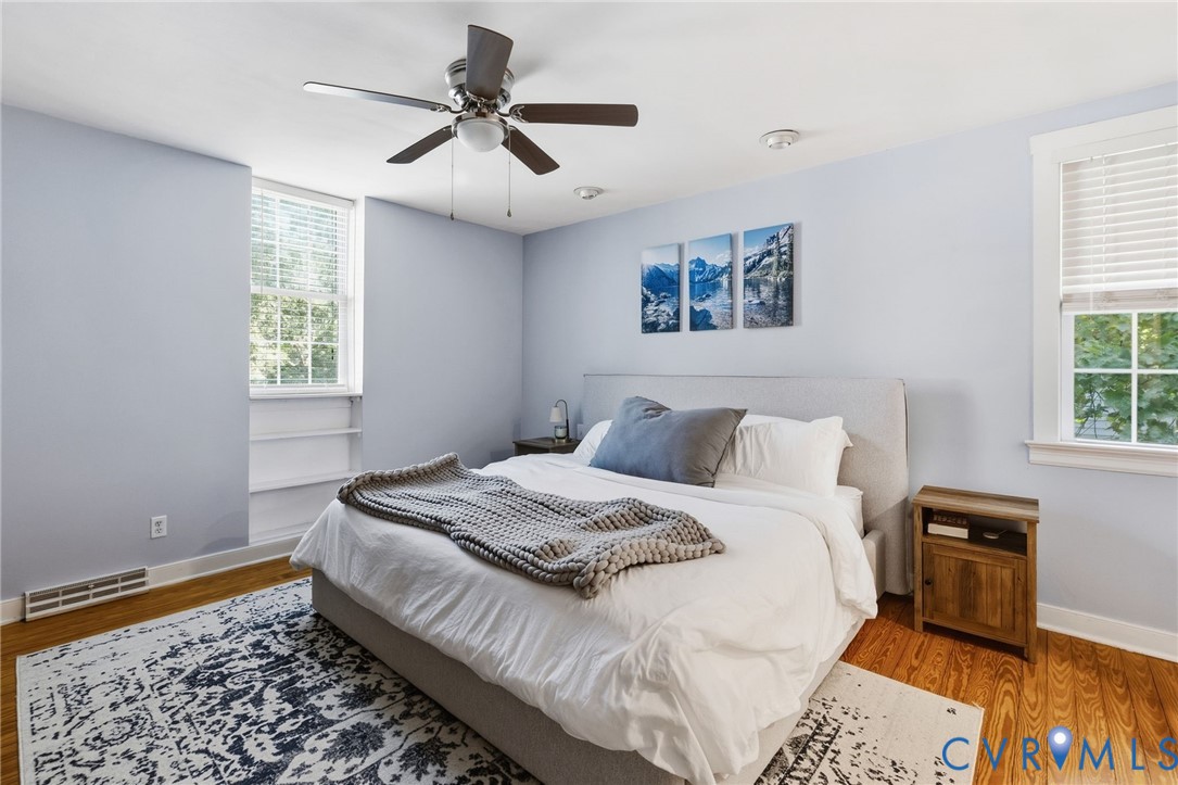 Hardwood flooring, recessed lighting, ceiling fan, two windows with blinds, and built-in shelving