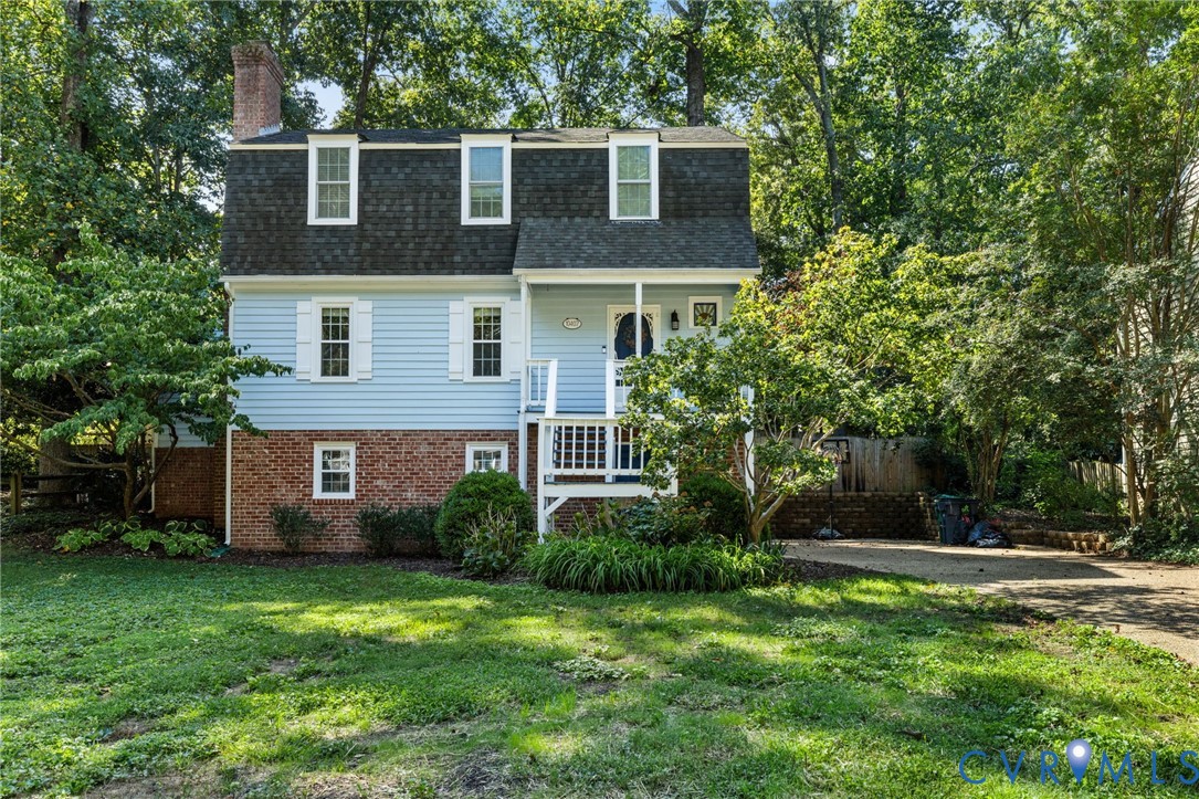 Dormer windows, light blue siding, brick foundation, front porch, and mature trees Dormer windows, light blue siding, brick foundation, front porch, and mature trees