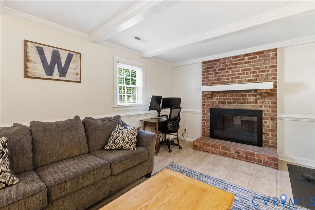 Exposed brick fireplace with a white mantel, tiled hearth, and a window with white blinds