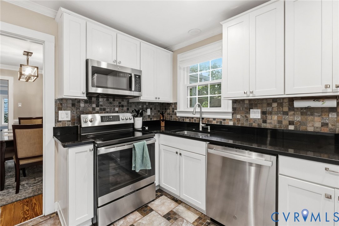 White shaker cabinetry with dark countertops, stainless steel appliances, and a mosaic tile backsplash