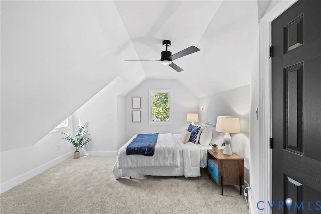 Vaulted ceilings, recessed window, dark paneled door, ceiling fan, and carpeted flooring
