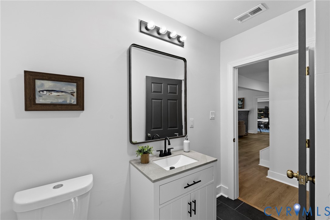 White vanity with a stone countertop, an integrated sink, and a matte black faucet