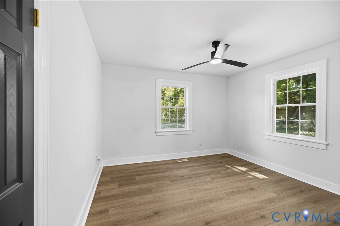 Wood-finish flooring, white walls, and a modern ceiling fan with lighting
