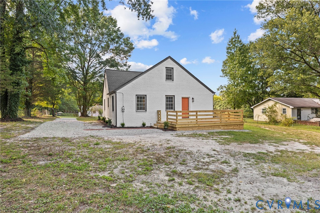 White exterior with dark trim windows, gabled roof, and an exterior wood deck