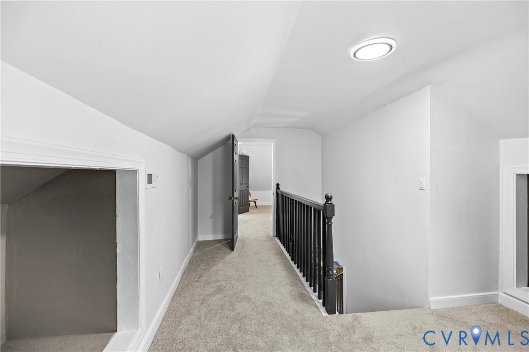 Carpeted hallway with white walls, black handrail, and flush-mount ceiling light