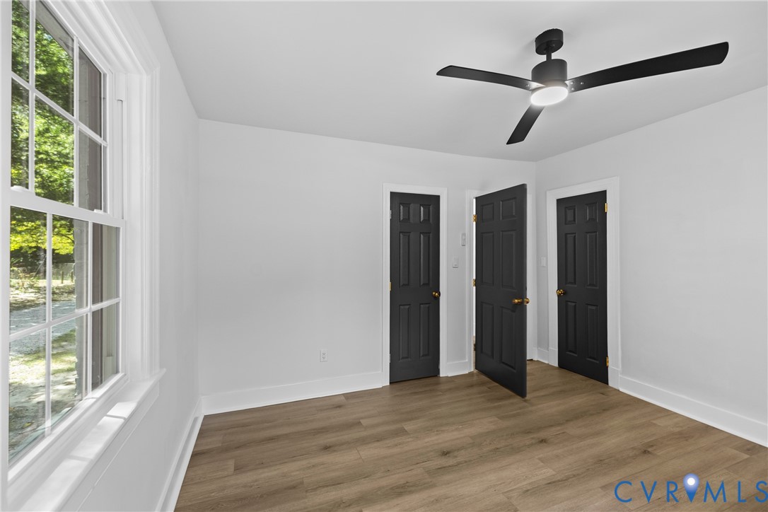 Bright interior with wood-finish flooring, white walls, and a multi-pane window