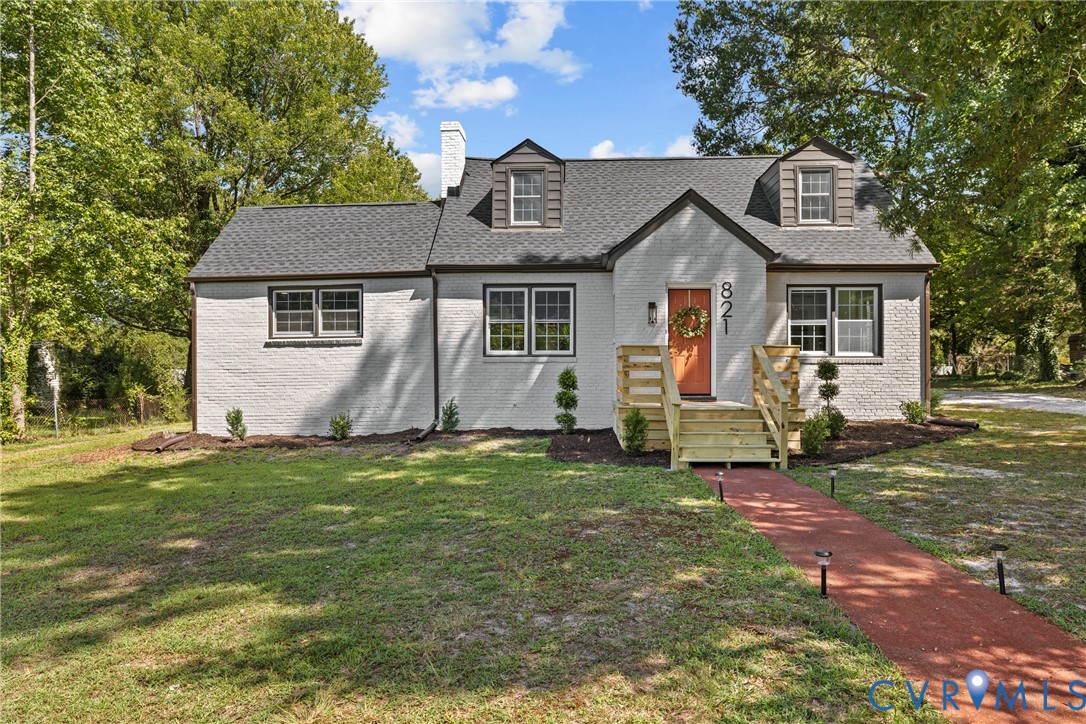 White painted brick exterior with dormer windows, new front porch and steps, red brick paver walkway, and mature trees