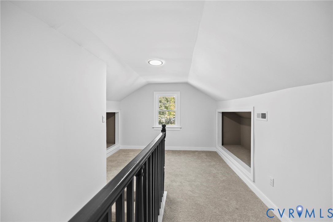 Carpeted loft area with sloped ceilings, a single window, recessed lighting, and built-in storage alcoves