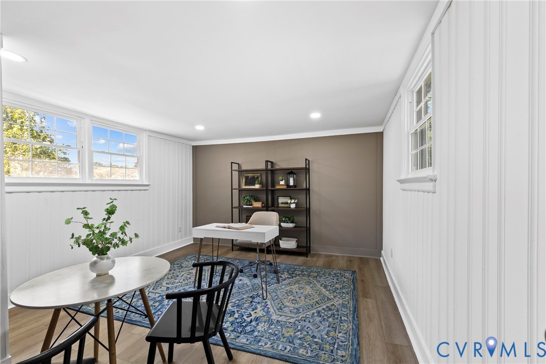 Recessed ceiling lighting, wood-finish flooring, white paneled wall accents, multiple windows, and crown molding