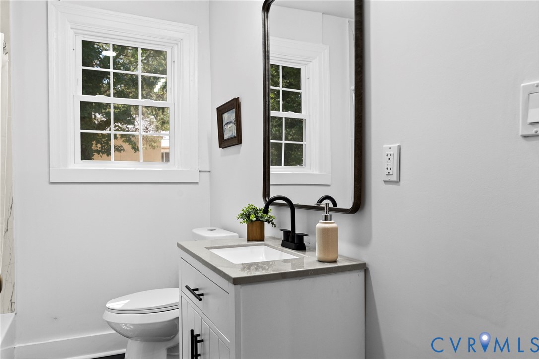 White vanity with a neutral countertop, dark hardware, and a black faucet