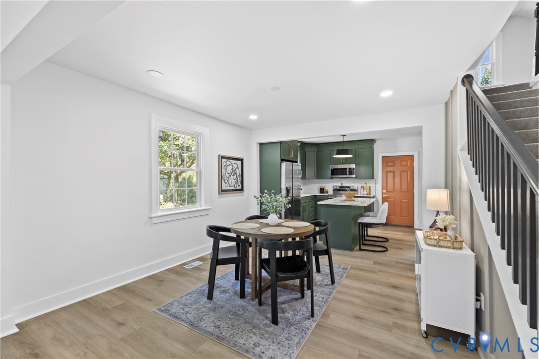 Open concept living area featuring wood-finish flooring, recessed lighting, and a kitchen with dark green cabinetry and a white countertop