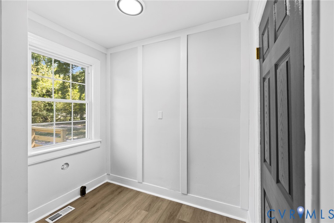 Recessed ceiling lighting, wood-finish flooring, paneled interior door, and panel wall detailing