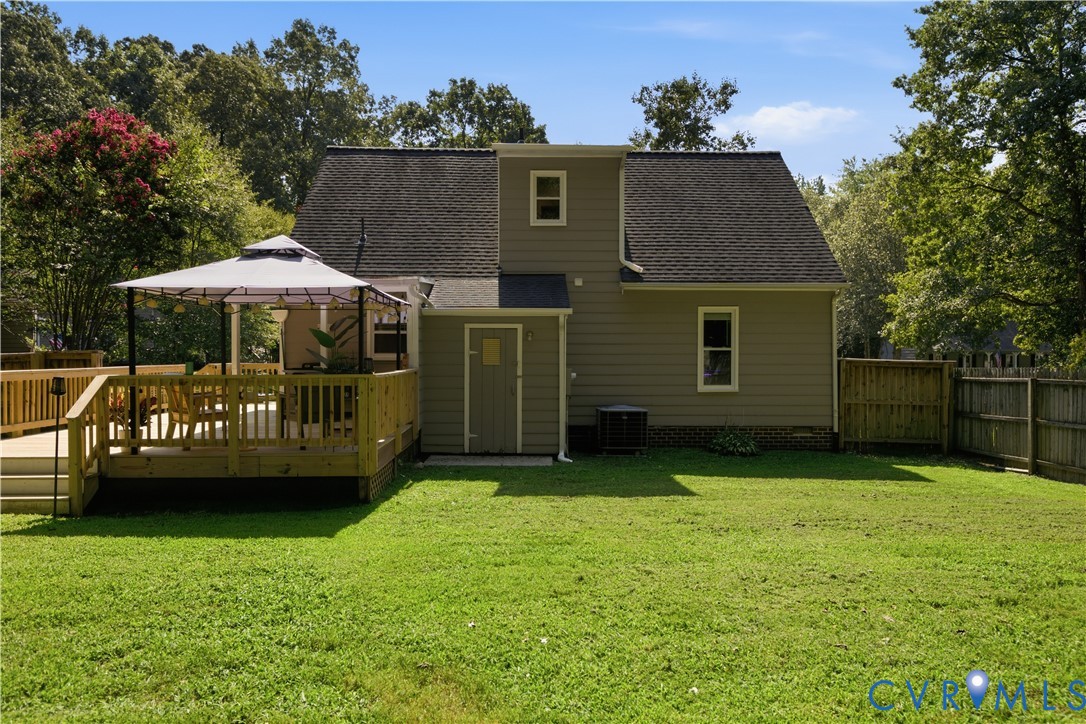 Expansive backyard featuring a manicured lawn, a multi-level wood deck, and a privacy fence