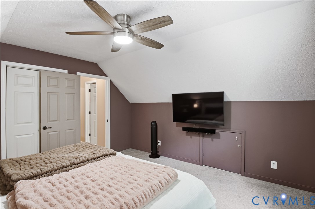 Carpeted flooring, ceiling fan with integrated lighting, two-tone wall treatment, and built-in storage access