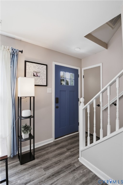 Blue front door with glass lites, wood-finish flooring, and white painted balusters