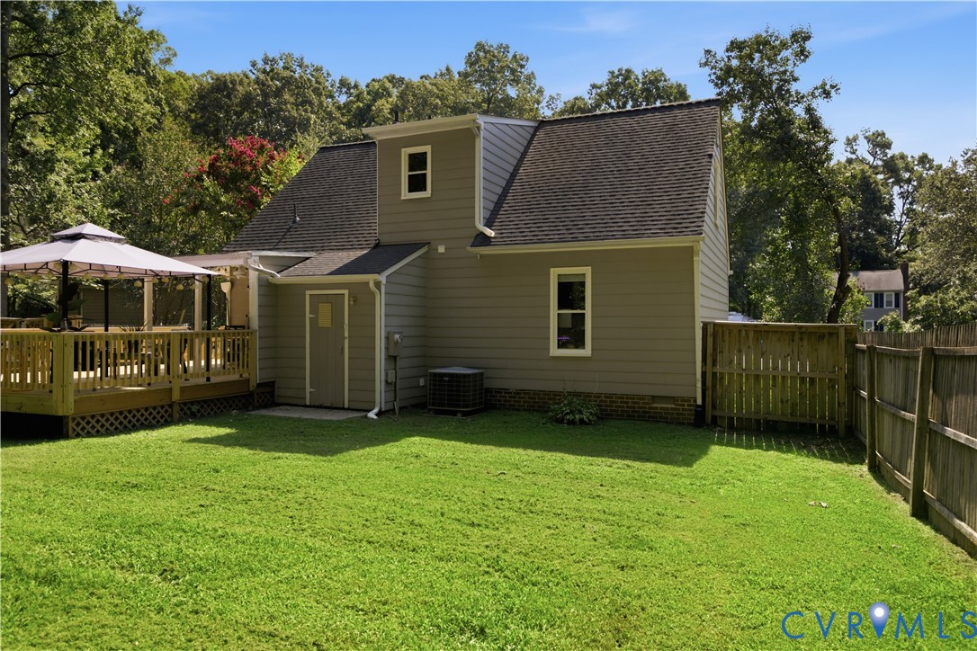 Expansive backyard featuring a manicured lawn, a wooden deck, and a privacy fence