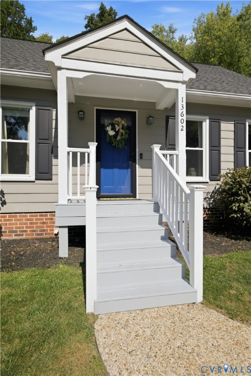 Covered front porch with white railings, a blue entry door, and exterior sconce lighting
