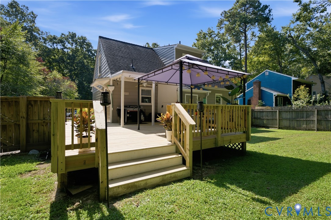 Expansive backyard featuring a multi-level wood deck, mature trees, and a wooden privacy fence
