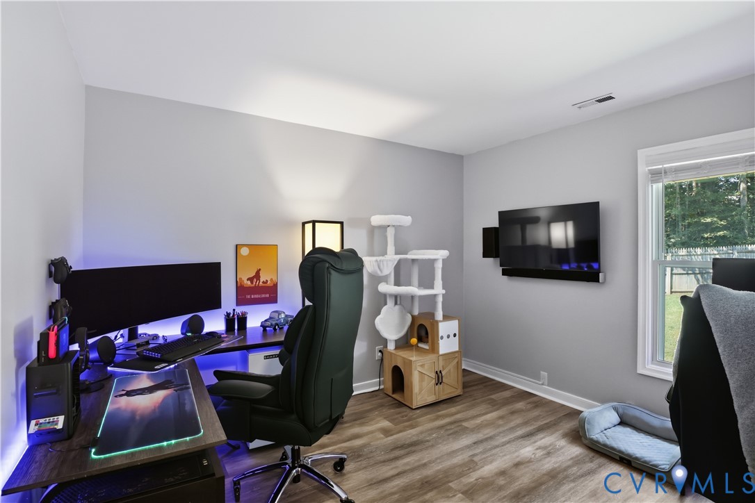 Wood-finish flooring with light gray walls and a single window. BEDROOM/OFFICE
