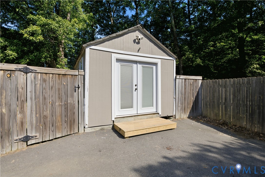 Shed with double glass-panel doors, exterior security camera, and wood step