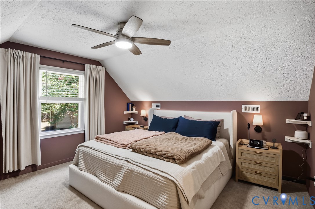 Sloped ceiling with a ceiling fan, window with blinds, wall-mounted sconce lighting, and built-in wall shelving
