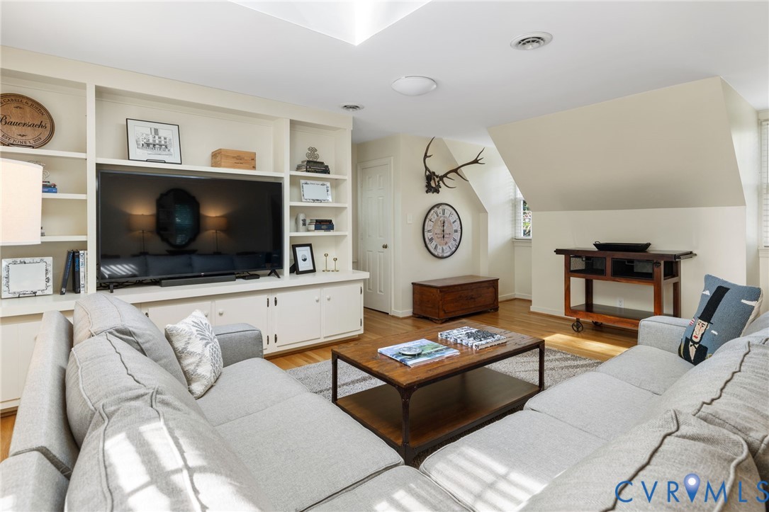 Built-in media center with shelving and lower cabinetry, wood-finish flooring, recessed lighting, and sloped ceiling