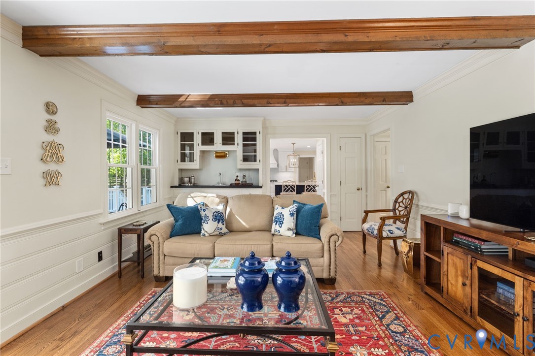 Hardwood flooring, exposed wood beams, built-in wet bar, white paneling, and double windows