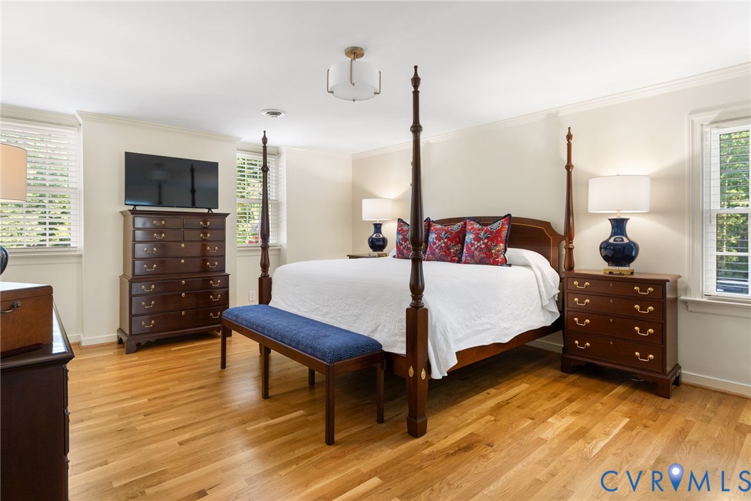 Hardwood flooring, crown molding, and multiple windows with blinds