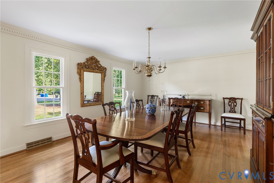 Hardwood flooring, crown molding, decorative chandelier, built-in display cabinet, and a built-in sideboard
