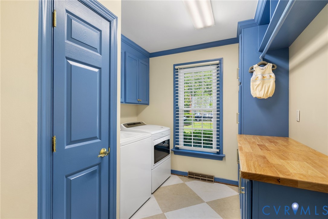 Laundry area featuring a window, built-in cabinetry, wood-finish countertop, and checkered flooring