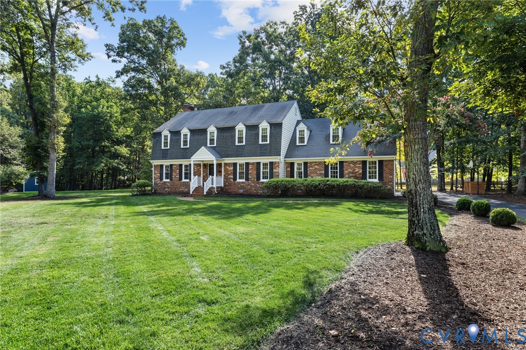 Brick exterior with white trim, a gambrel roof, and multiple dormer windows