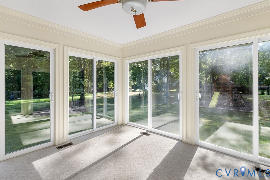 Sunroom with multiple sliding glass doors, a ceiling fan, and carpeted flooring