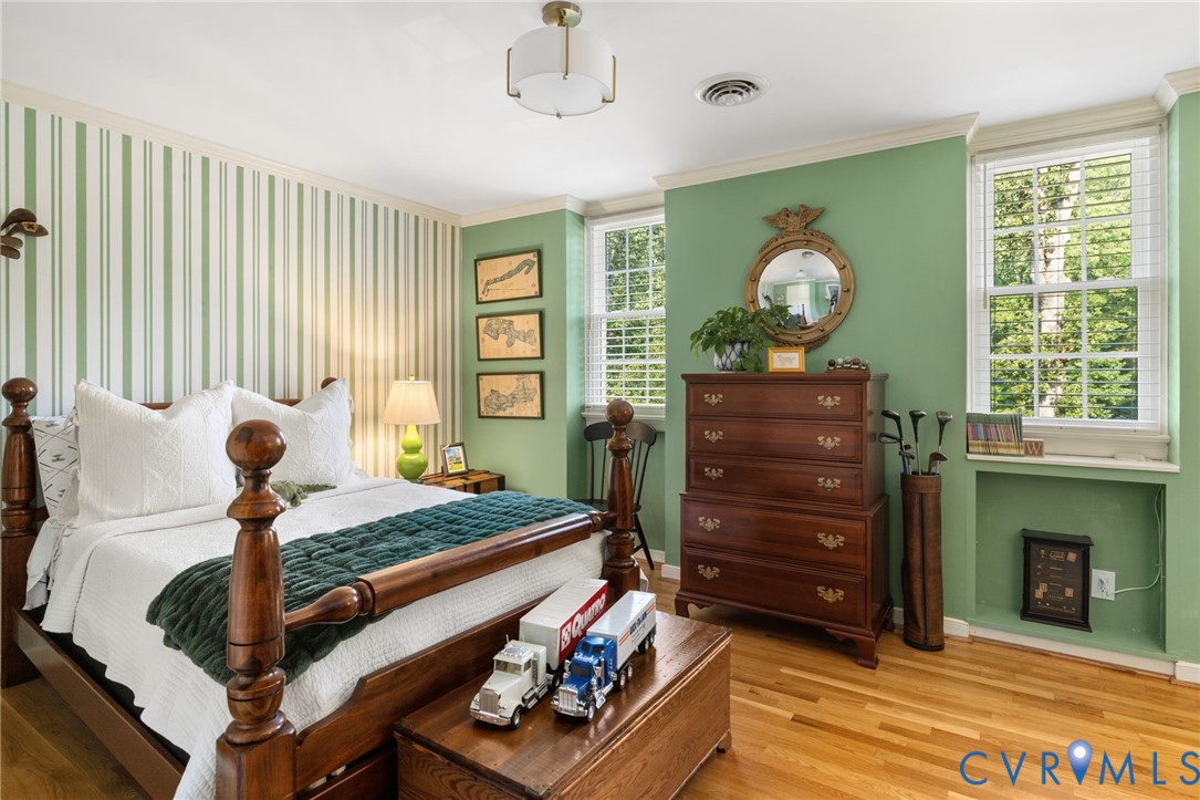 Hardwood flooring, painted walls, crown molding, and two windows with blinds