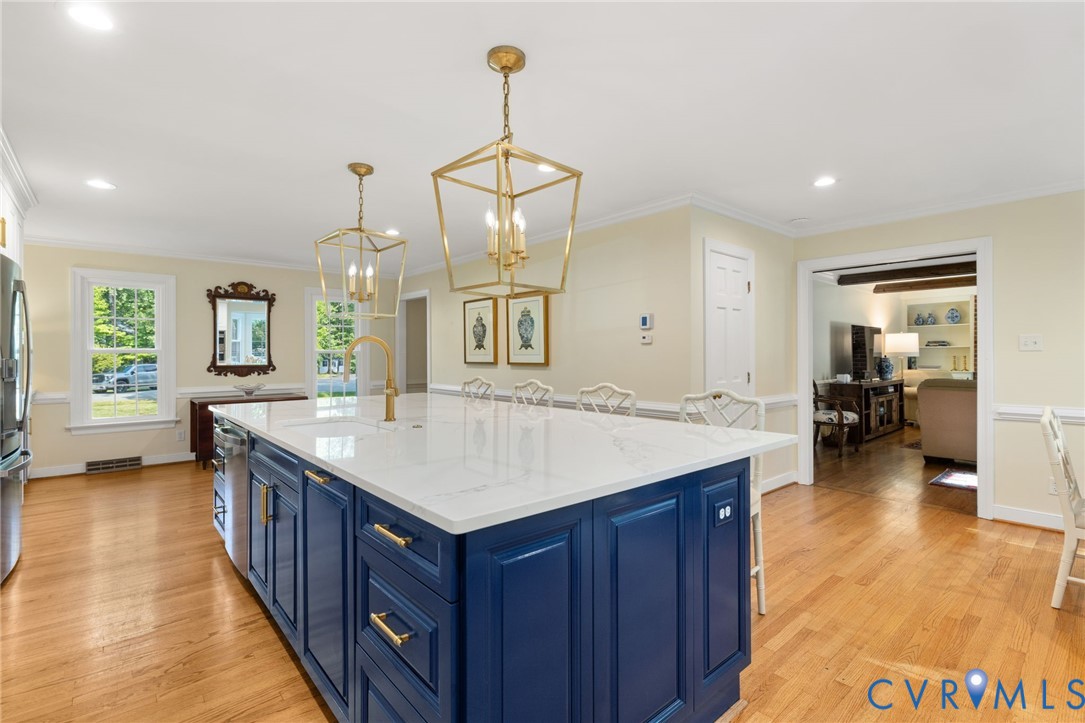 Kitchen island with a white countertop and blue cabinetry, brass hardware, and a brass faucet